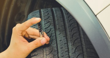 Main en train de mesurer l'usure d'un pneu voiture
