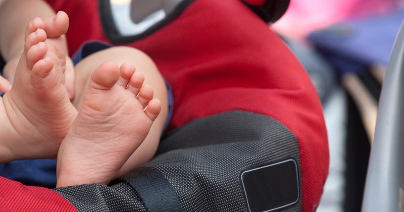 Pieds d'un bébé installé dans un siège auto