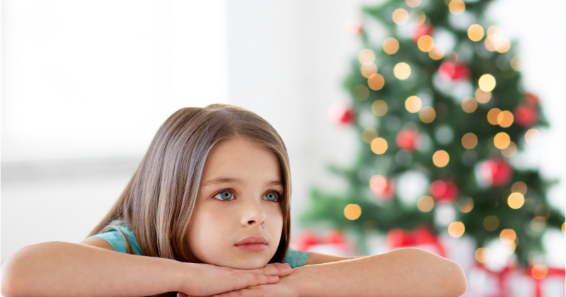 Petite fille qui s'ennuie avec en arrière plan un sapin de Noël