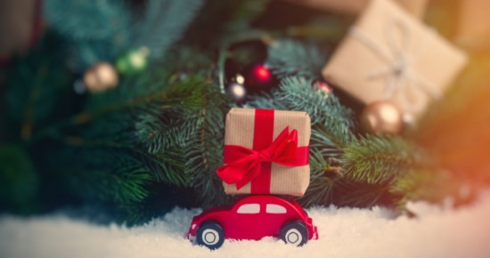 Petite voiture avec cadeau au pied d'un sapin de Noël