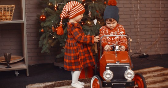 Petits enfants devant avec une vielle voiture modèle réduit devant un sapin de Noël