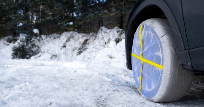 Roue de voiture équipée de chaussette à neige, sur une route enneigée et verglacée