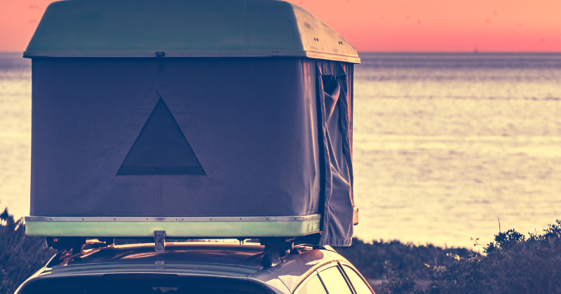 Tente de toit rigide installée sur une voiture, face à  la mer