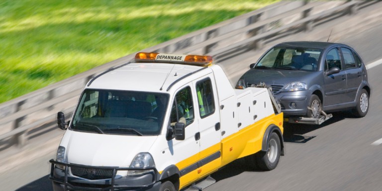 Crevaison sur autoroute, voiture remorquée par le camion de dépannage